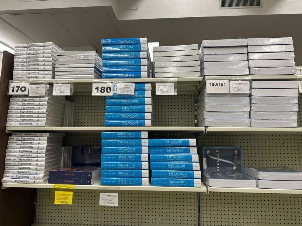 Academic books stacked with class information at the book store.