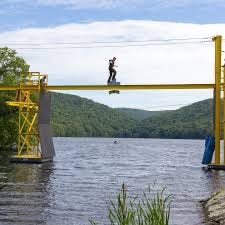 U.S. Army cadet at Recondo water obstacle area.  Balancing on beam over water, with Recondo sign hanging from beam.  Biography of Dr. Anthony J. Carbone.