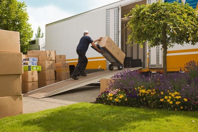 Man wheeling stack of boxes up ramp into a moving van.  Autobiography of Dr. Anthony J. Carbone.