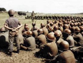 Group of Army cadets in olive drab fatigues with steel pot helmets listening to an instructor.  Biography of Dr. Anthony J. Carbone.