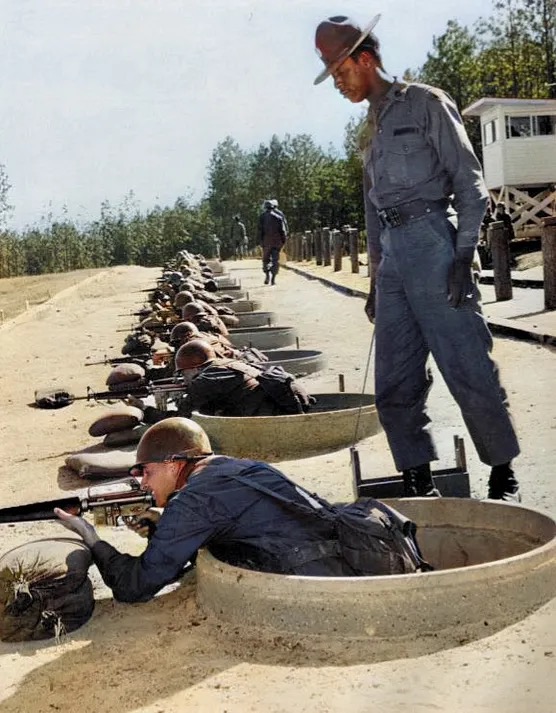 Soldiers in fatigues circa 1970s firing M16A1 rifles on a firing range.  Biography of Dr. Anthony J. Carbone.