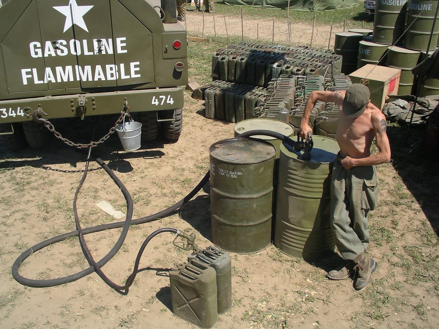 Photograph of a soldier pumping gasoline into 55 gallon drums preparing to make thickened fuel. Biography of Dr. Anthony J. Carbone.