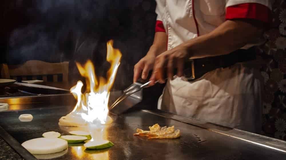 Hibachi chef cooking a flaming dish on the hibachi table. Biography of Dr. Anthony J. Carbone.