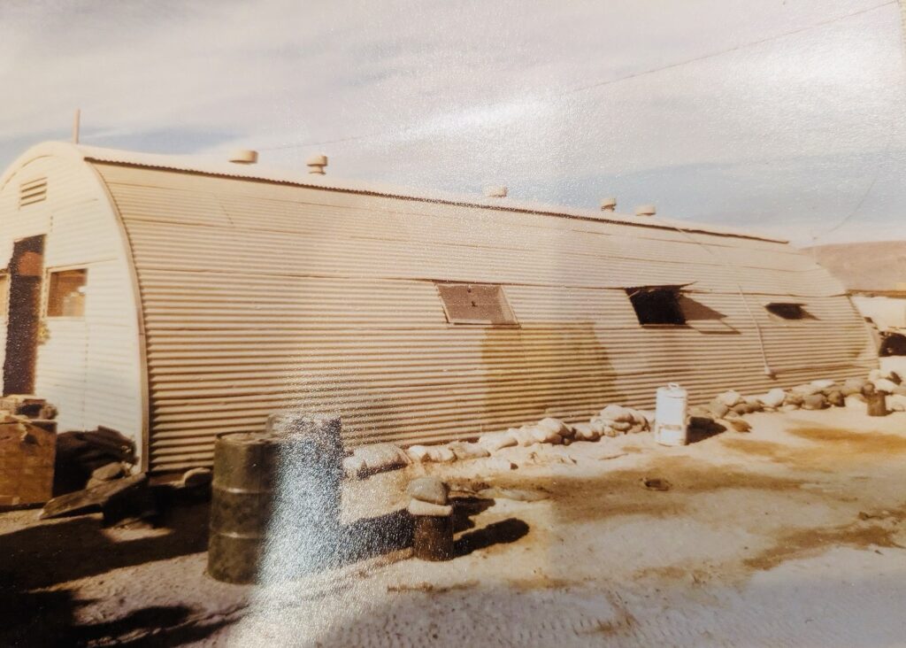 Photograph of desert sand color Quonset Hut building that housed my office and members of Range Control at Fort Irwin, California.  Biography of Dr. Anthony J. Carbone.