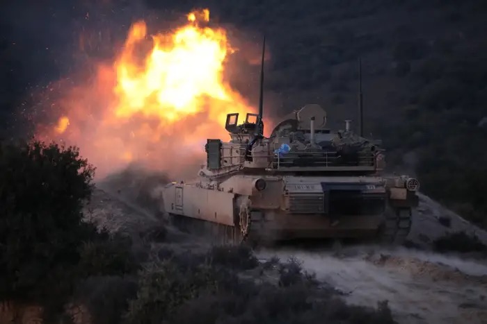 M1 Abrams tanks firing at night at the Live Fire Range at the National Training Center at Fort Irwin, California.  Biography of Dr. Anthony J. Carbone.