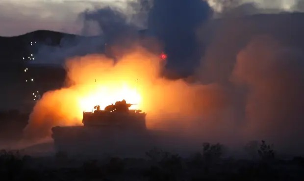 M1 Abrams tanks firing at night at the Live Fire Range at the National Training Center at Fort Irwin, California.  Biography of Dr. Anthony J. Carbone.