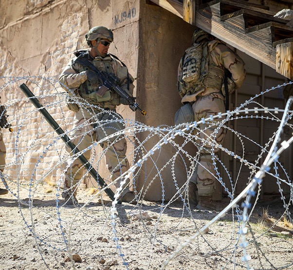 Infantry clearing barbed wire obstacles at the National Training Center at Fort Irwin, California.  Biography of Dr. Anthony J. Carbone.